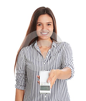 Happy young woman operating air conditioner with remote control on white