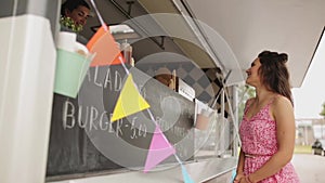 Happy young woman ordering meal at food truck