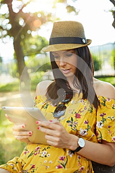 Happy young woman outdoor in summer using tablet