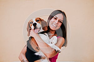 Happy young woman outdoors having fun with beagle dog. Family and lifestyle concept. yellow background