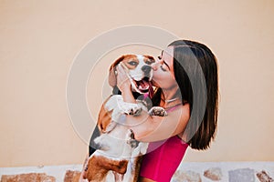 Happy young woman outdoors having fun with beagle dog. Family and lifestyle concept. yellow background