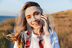 Happy young woman outside in free alternative vacation camping talking by mobile phone