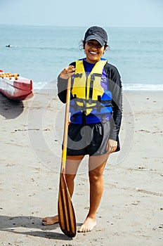 Happy young woman with paddle on beach