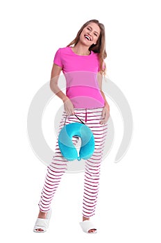 Happy young woman in pajamas with neck pillow on white
