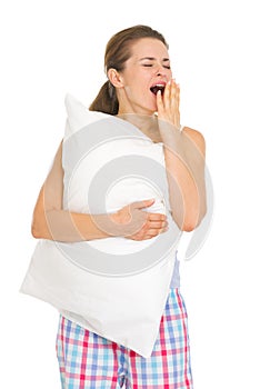 Happy young woman in pajamas with pillow yawing photo