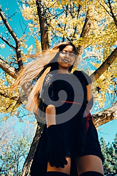 Happy young woman in park on sunny autumn day, smiling. Cheerful beautiful girl in black retro dress autumn fashion style