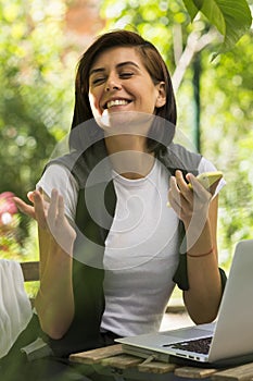 Happy young woman with phone and laptop