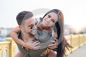 Happy young woman piggyback on man outdoors