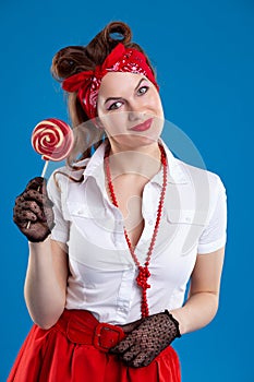 Happy young woman in pin-up style with candy Lollipop, on blue isolated background