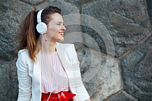 happy young woman in pink dress and white jacket in city