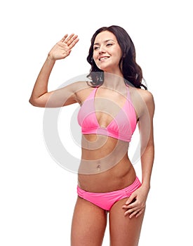 Happy young woman in pink swimsuit waving hand