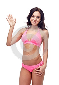 Happy young woman in pink swimsuit waving hand