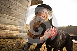 Happy young woman plaing with her black dog Brovko Vivchar in fron of old wooden house