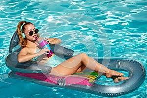 Happy young woman playing with colorful swim ring in swimming pool on summer day. Water toys. Girl in tropical resort