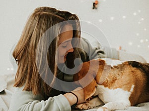 Happy young woman playing with her dog on a white background. Beagle dog with owner. Girl and dog at home