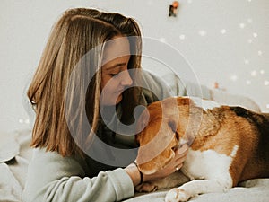 Happy young woman playing with her dog on a white background. Beagle dog with owner. Girl and dog at home