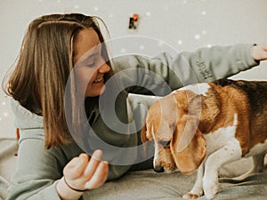 Happy young woman playing with her dog on a white background. Beagle dog with owner. Girl and dog at home