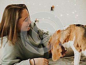 Happy young woman playing with her dog on a white background. Beagle dog with owner. Girl and dog at home