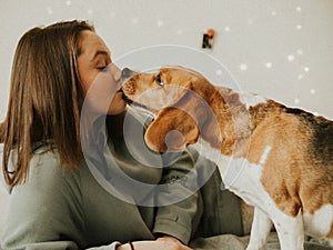 Happy young woman playing with her dog on a white background. Beagle dog with owner. Girl and dog at home