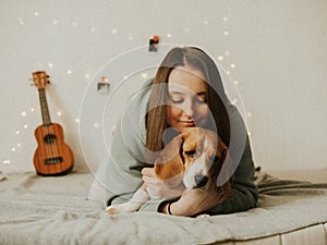 Happy young woman playing with her dog on a white background. Beagle dog with owner. Girl and dog at home