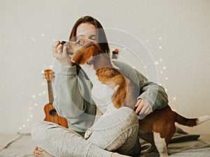 Happy young woman playing with her dog on a white background. Beagle dog with owner. Girl and dog at home