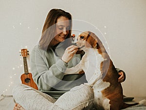 Happy young woman playing with her dog on a white background. Beagle dog with owner. Girl and dog at home