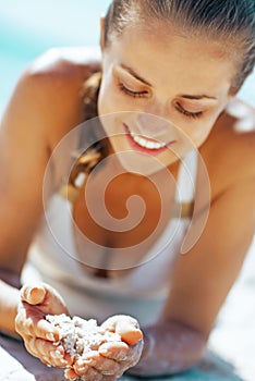 Happy young woman playing with sand on beach