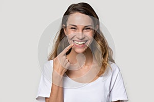 Happy young woman pointing finger at toothy healthy smile