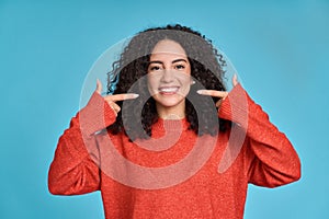 Happy young woman pointing at white healthy teeth, showing perfect dental smile.