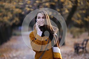 Happy young woman portrait in autumn park using phone