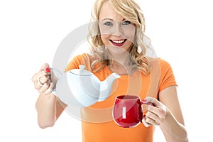 Happy Young Woman Pouring Tea from a Teapot