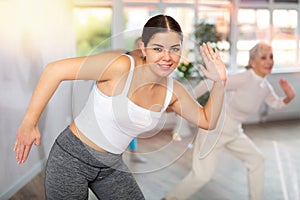 Happy young woman practicing aerobics in light fitness studio