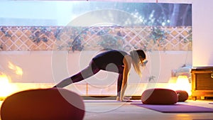 Happy young woman practicing yoga on the empty class at sunset.