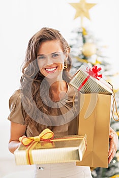 Happy young woman present boxes in front of christmas tree