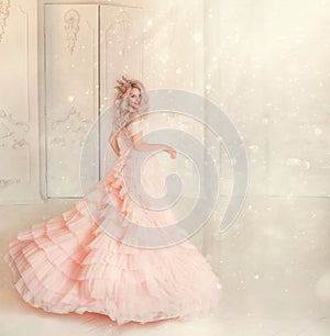 Happy young woman princess dancing in lush vintage pink dress. white royal room. Queen blond hair, golden crown.