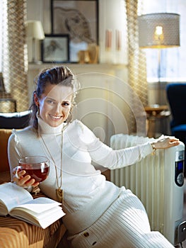 Happy young woman and radiator and reading book with tea cup