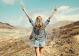 Happy young woman raises hands up on a hiking trail on top of the mountain, view from the back, Tenerife, Canary Islands