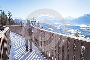 Happy young woman is raising her hands on the mountain, enjoying the view over Salzburg. Winter time on Gaisberg, Salzburg,