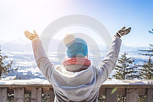 Happy young woman is raising her hands on the mountain, enjoying the view over Salzburg. Winter time on Gaisberg, Salzburg,