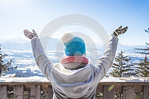 Happy young woman is raising her hands on the mountain, enjoying the view over Salzburg. Winter time on Gaisberg, Salzburg,