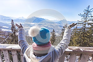 Happy young woman is raising her hands on the mountain, enjoying the view over Salzburg. Winter time on Gaisberg, Salzburg,