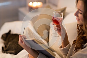 Happy young woman reading book in bed at home