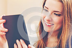 Happy young woman reading an e-book on her couch