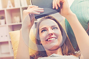 Happy young woman reading an e-book on her couch