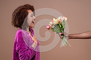 Happy young woman receiving flowers and looking pleased