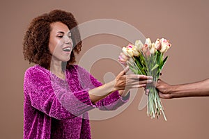 Happy young woman receiving flowers and looking pleased