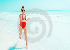 Happy young woman in red swimwear on seashore running