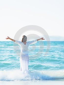 Happy young woman rejoicing on sea shore . rear view photo