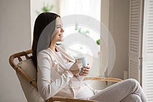 Happy young woman relax in chair drinking tea