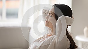 Happy young woman relax on sofa sleeping or dreaming